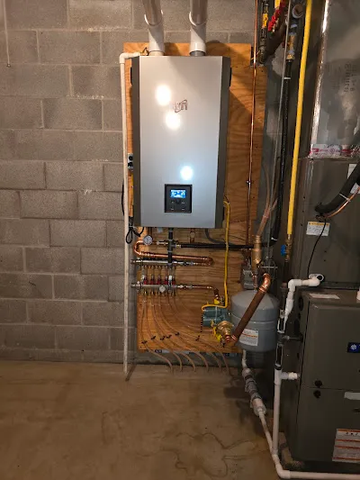 Wall-mounted high-efficiency boiler with copper distribution piping, manifolds, and condensing venting in a mechanical room.