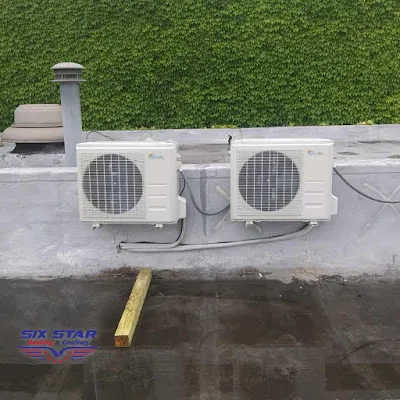 Two wall-mounted outdoor mini-split condensers with neat line hide, ivy backdrop, Six Star Heating & Cooling.